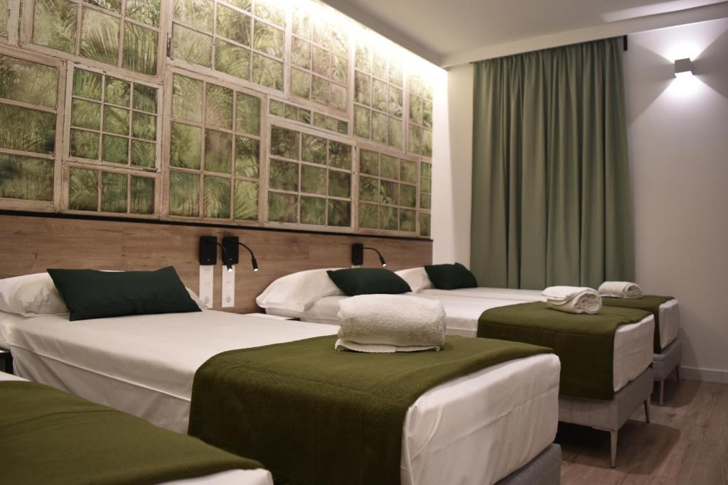 three beds in a room with green and white at Casp Green House in Barcelona