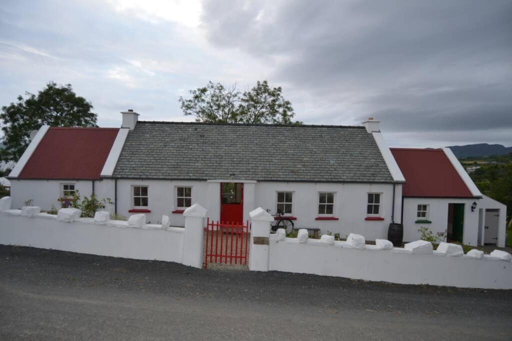una casa blanca con techos rojos y una valla blanca en Cecil's Cottage, Ballynary, Buncrana by Wild Atlantic Wanderer, en Buncrana