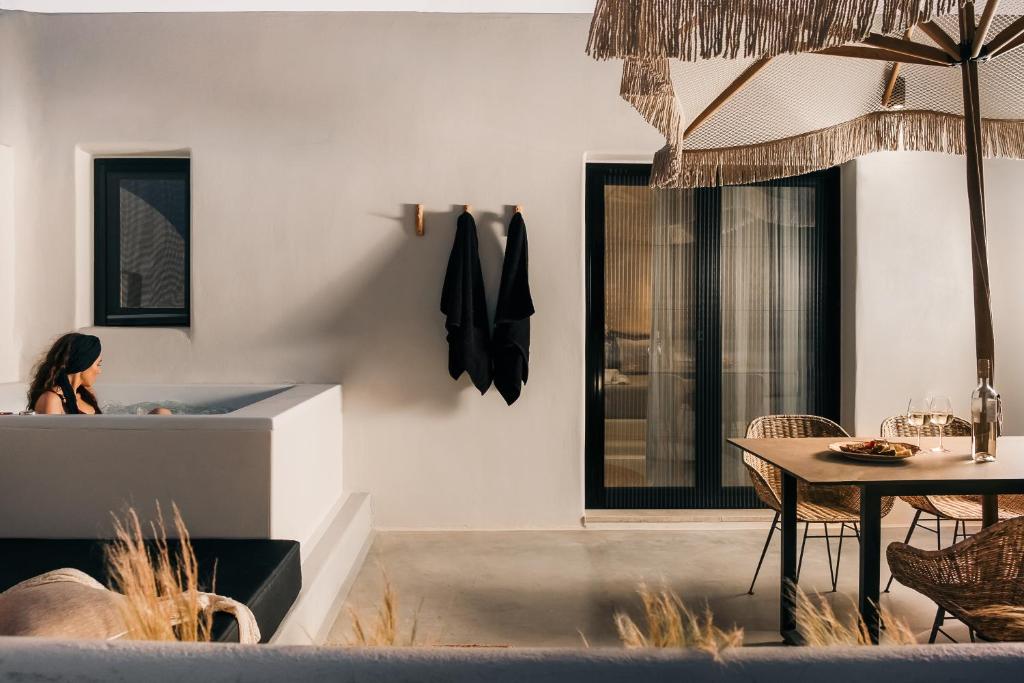 eine Frau in einer Badewanne in einem Zimmer mit einem Tisch in der Unterkunft Emery Hotel in Naxos Chora