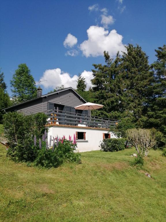 une maison avec un parasol au-dessus d'une cour dans l'établissement Chalet Dionysos, à Murat-le-Quaire
