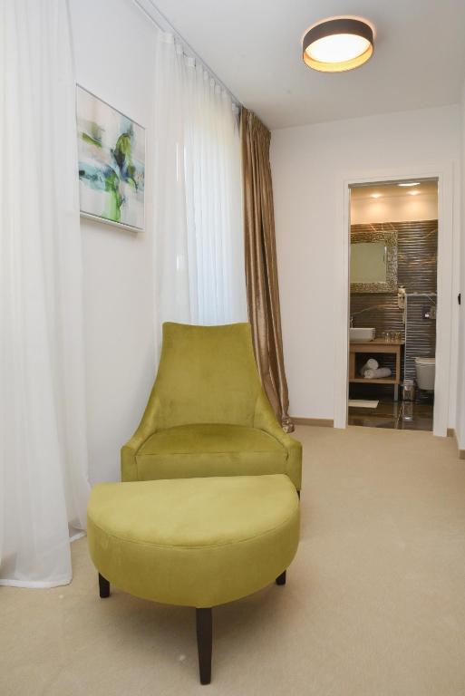 a yellow chair in a living room with a room at Hotel Meduza in Senj