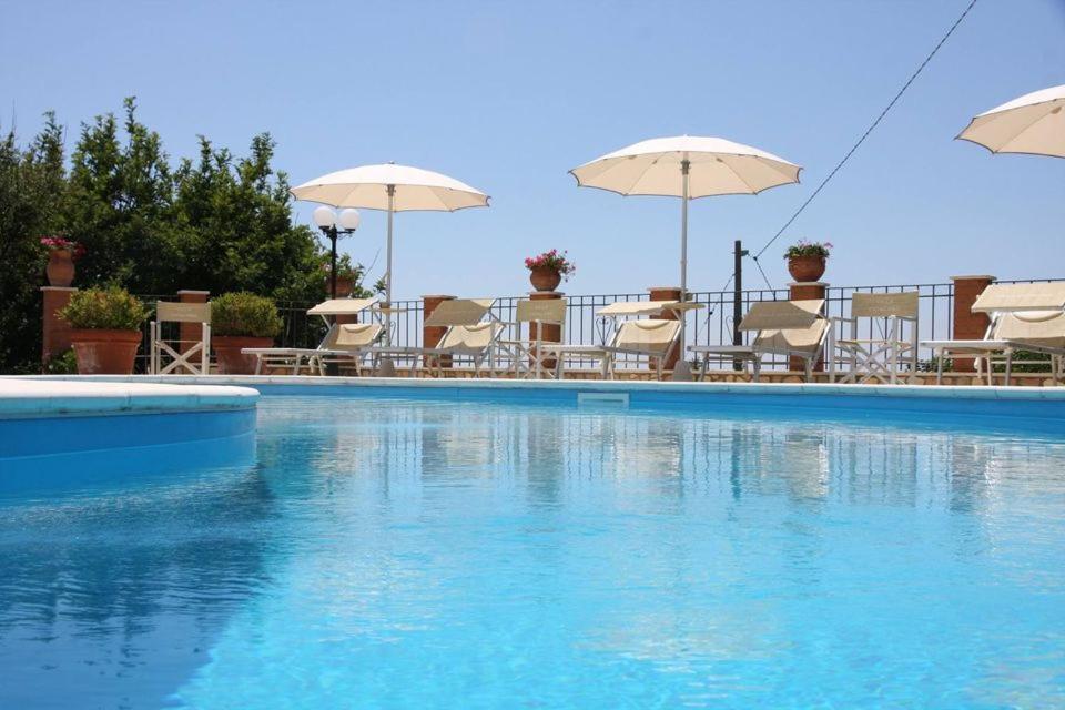 a swimming pool with chairs and umbrellas at Villa Catalano in Paola