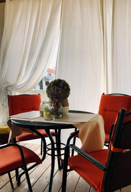 a table with two chairs and a table with flowers on it at Villa Dora - Mediterranean family house for 9 with private garden, BBQ, sea view and private parking for 4 cars in Pag