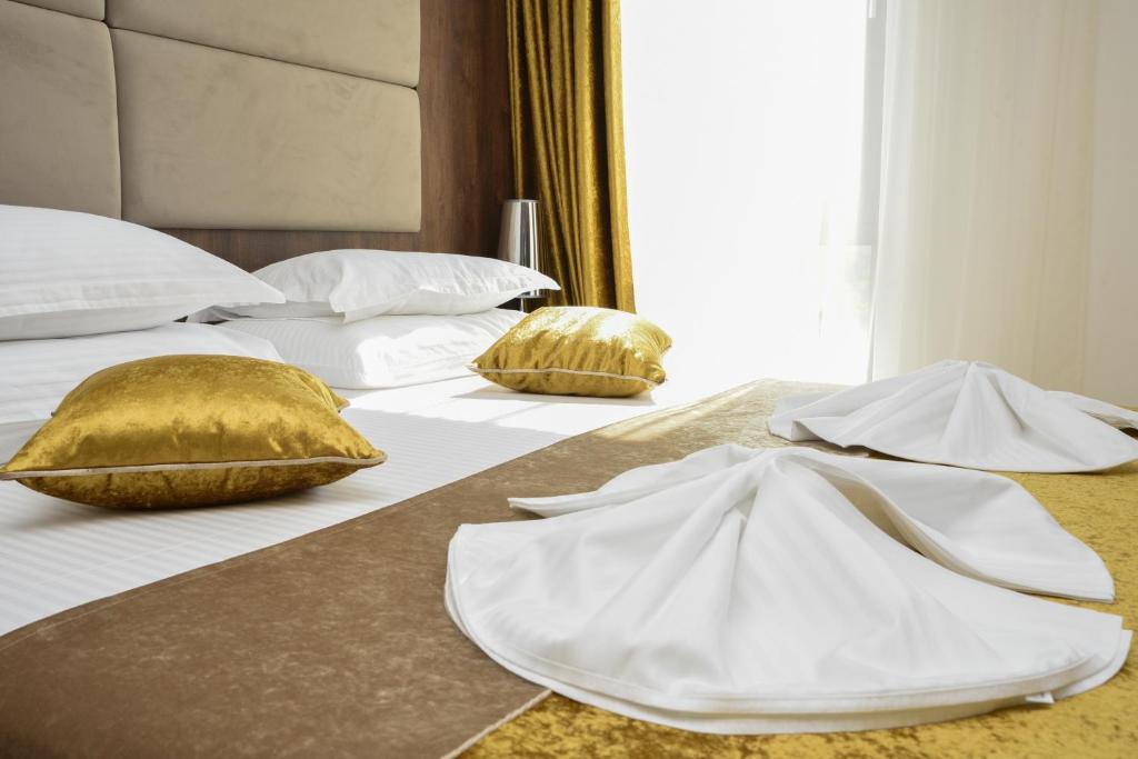 two beds with white and gold pillows on them at Hotel Meduza in Senj