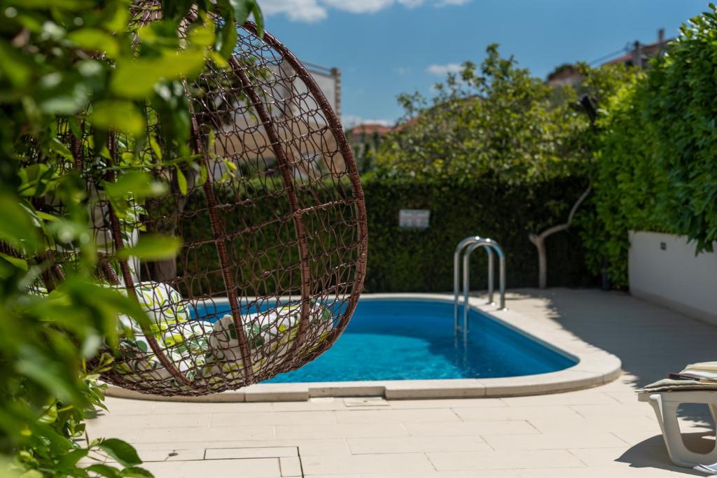 a swimming pool with a basket in a yard at Apartments Orlic in Trogir