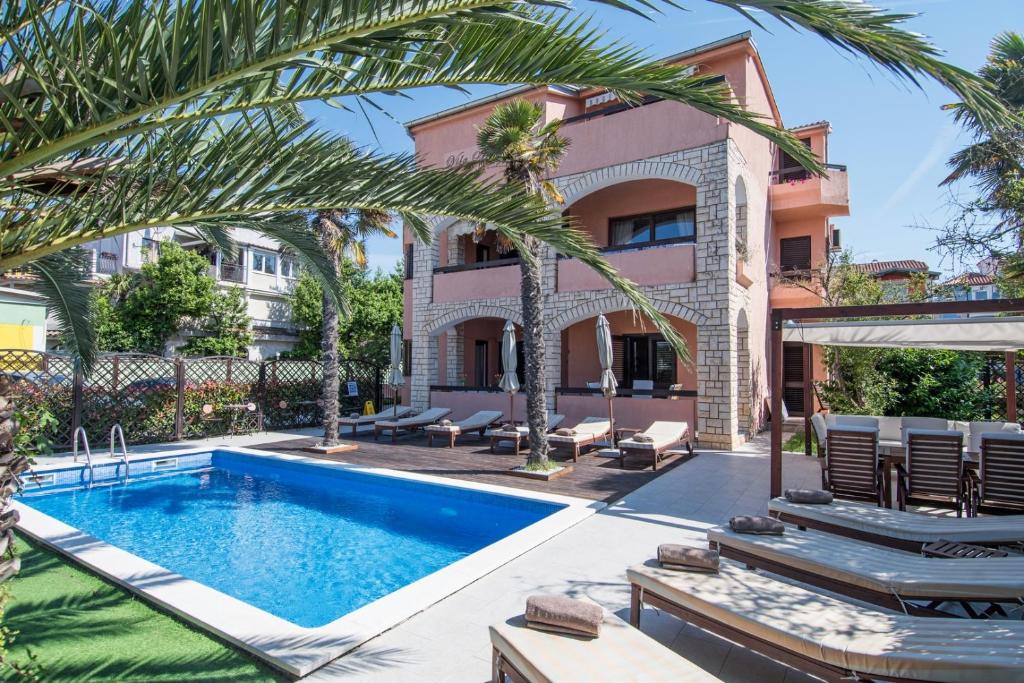 a villa with a swimming pool and palm trees at Breakfast & Bed Anita in Medulin
