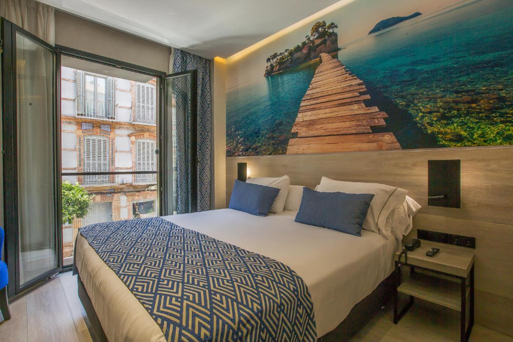 a bedroom with a bed and a painting on the wall at Hotel Brö-Adults Recommended in Málaga