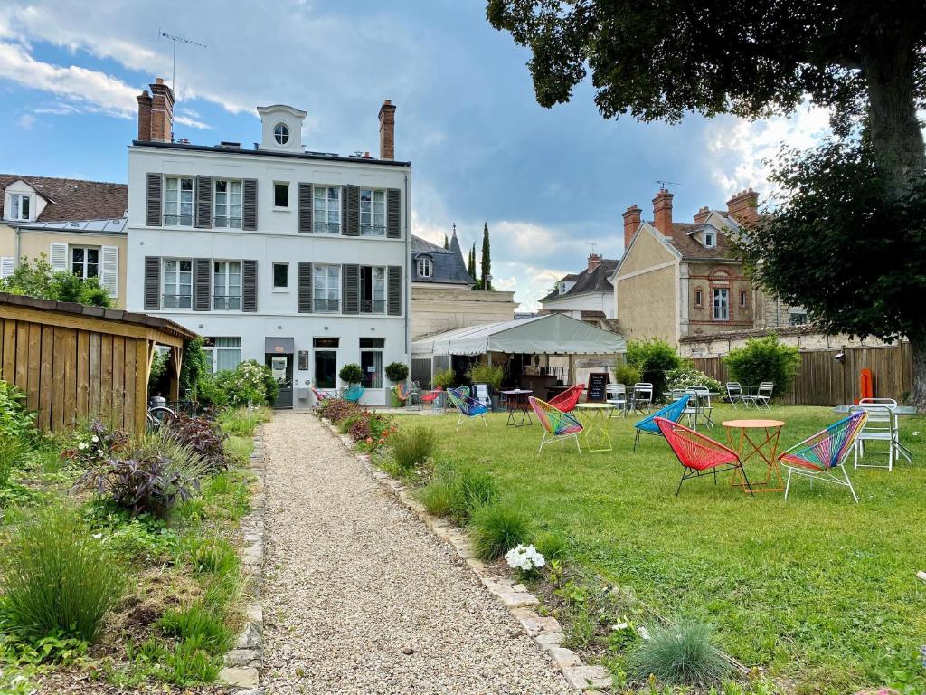 een groep stoelen in de tuin van een huis bij The Originals Boutique, Hôtel Victoria, Fontainebleau in Fontainebleau