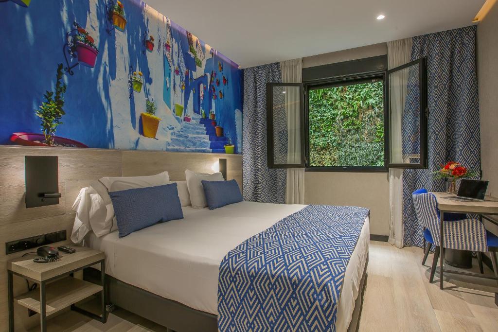 a bedroom with a bed and a desk and a window at Hotel Brö-Adults Recommended in Málaga