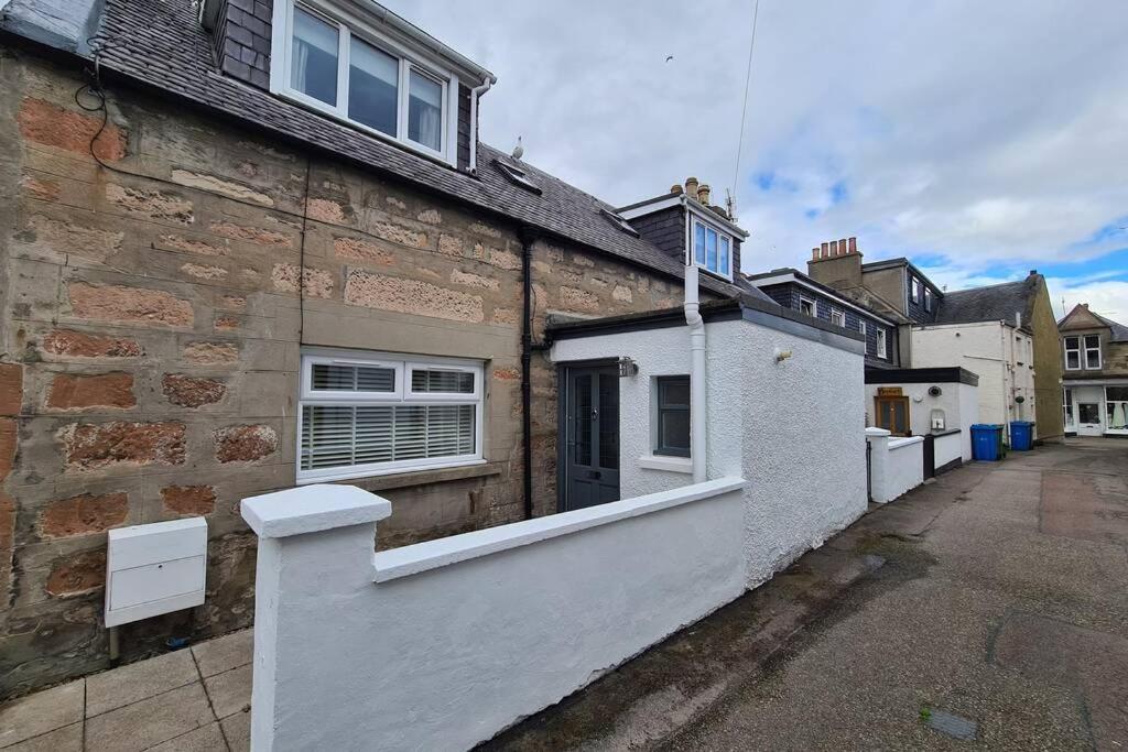 a brick house with a white fence in front of it at Shadow's Cottage situated in Fishertown, Nairn. in Nairn