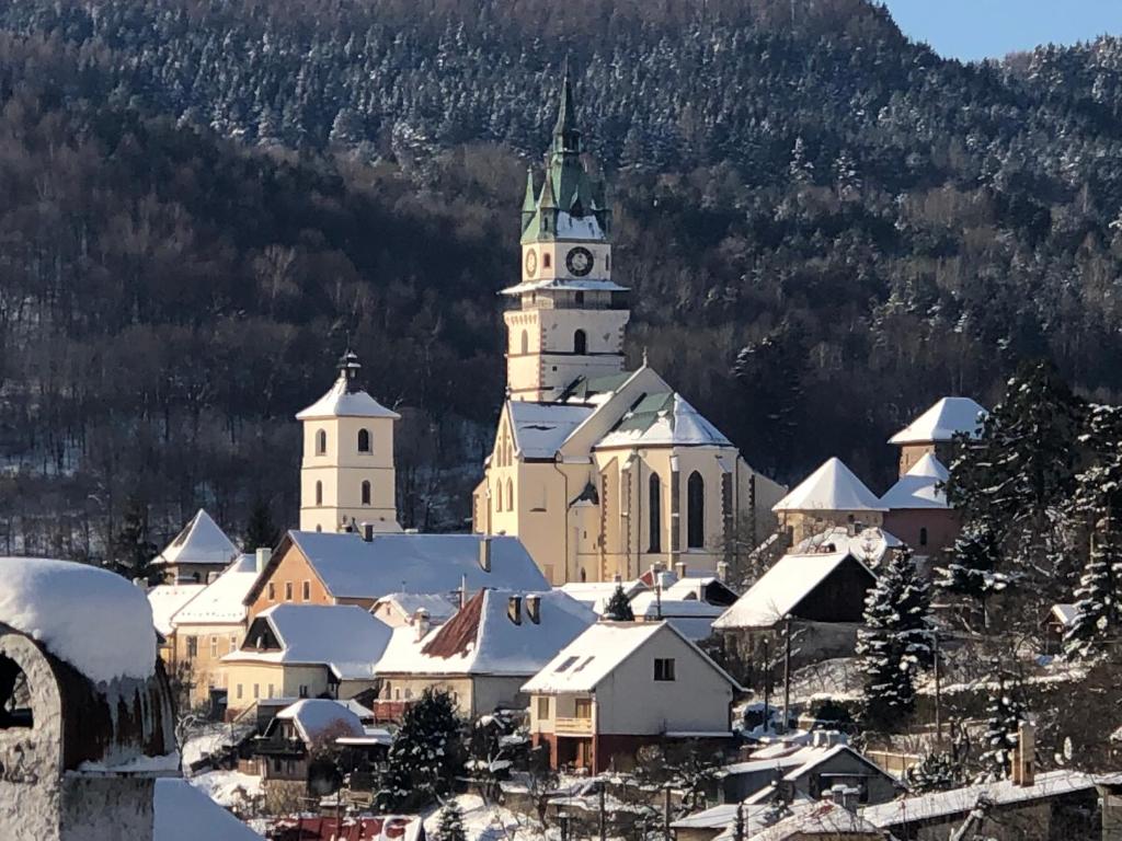 a large building with a clock tower in the snow at Apartmán v centre in Kremnica