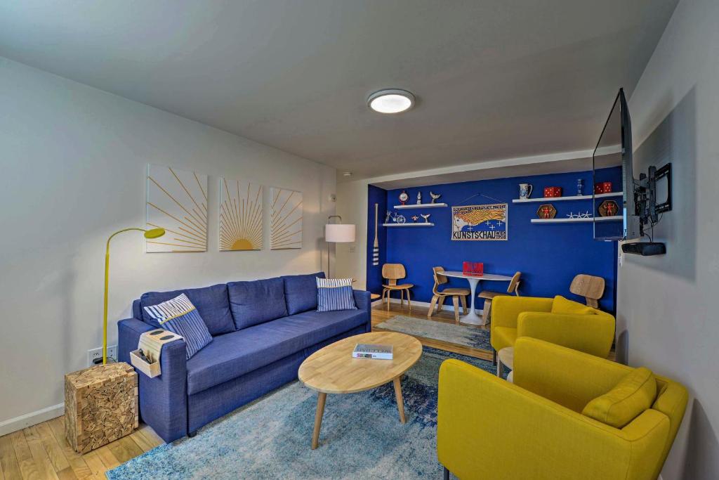 a living room with a blue couch and yellow chairs at Central and Contemporary NJ Condo Steps to Shore! in Asbury Park