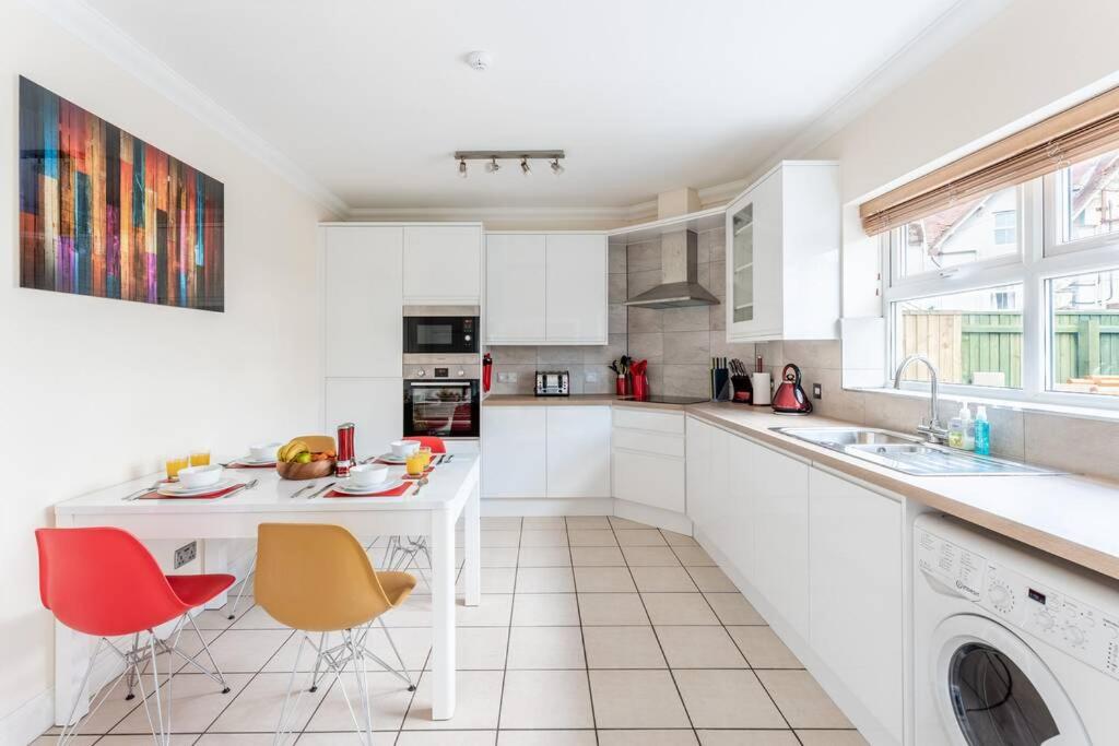 una cocina con armarios blancos y una mesa y sillas blancas. en Rockmount Court en Bournemouth