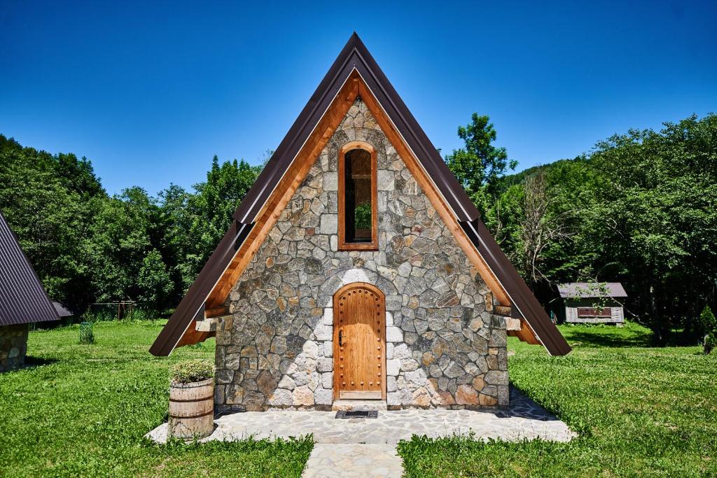 una pequeña capilla de piedra con puerta de madera en Houses Amanet en Kolašin