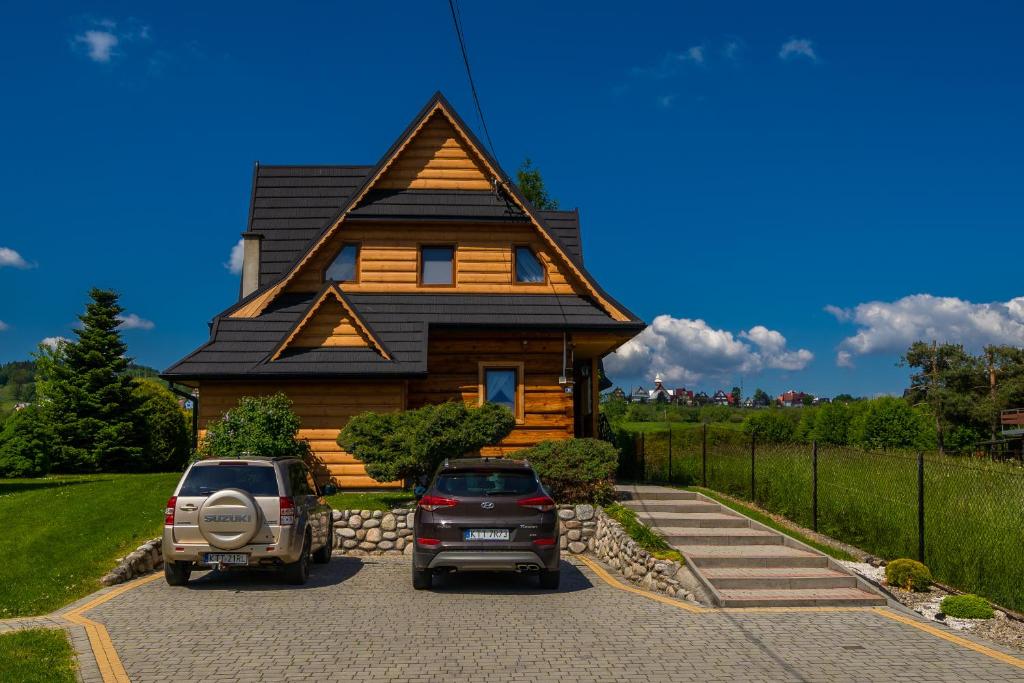 two cars parked in front of a log cabin at Podhalański Domek in Szaflary