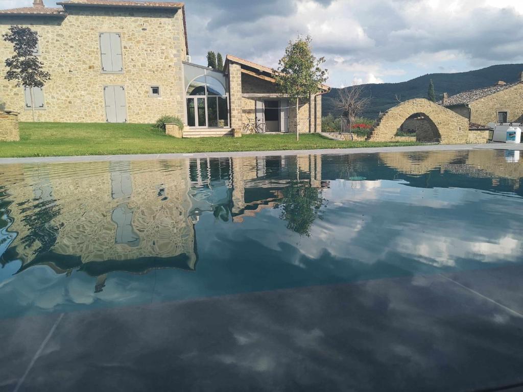 un riflesso di un edificio in una piscina d'acqua di Alba Morus Bed e Breakfast sentiti a casa nel cuore della Toscana ad Arezzo