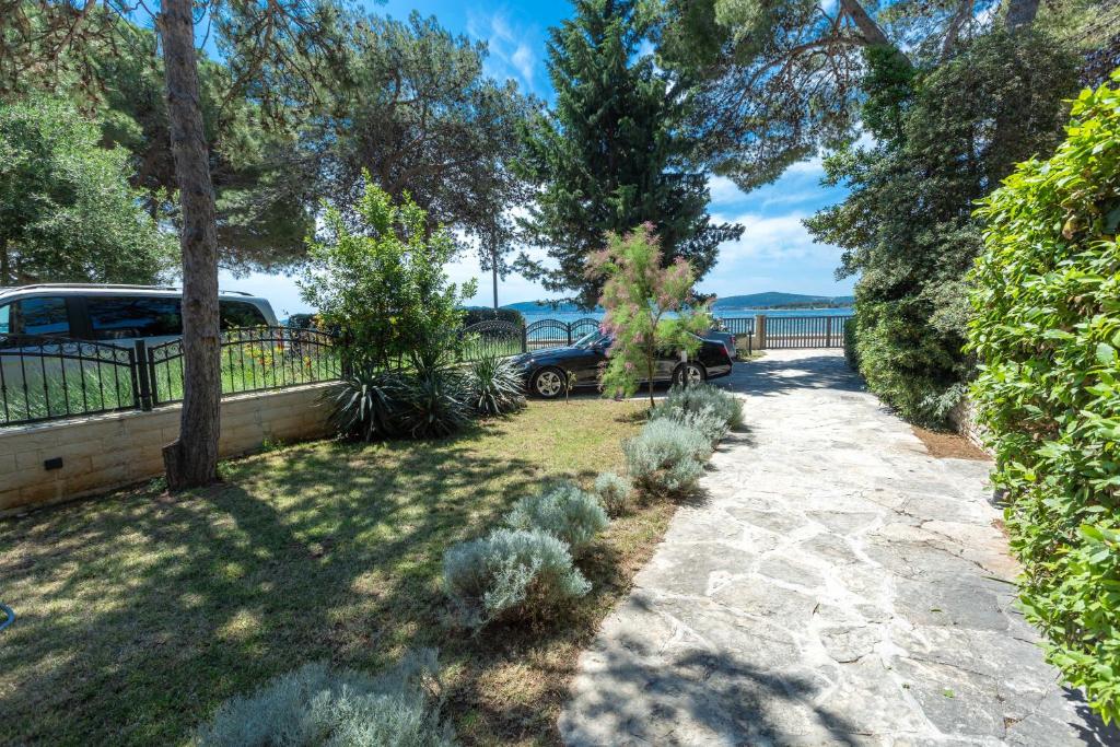 a garden with trees and cars parked on a sidewalk at Sea Sound Apartments Rea in Sveti Filip i Jakov