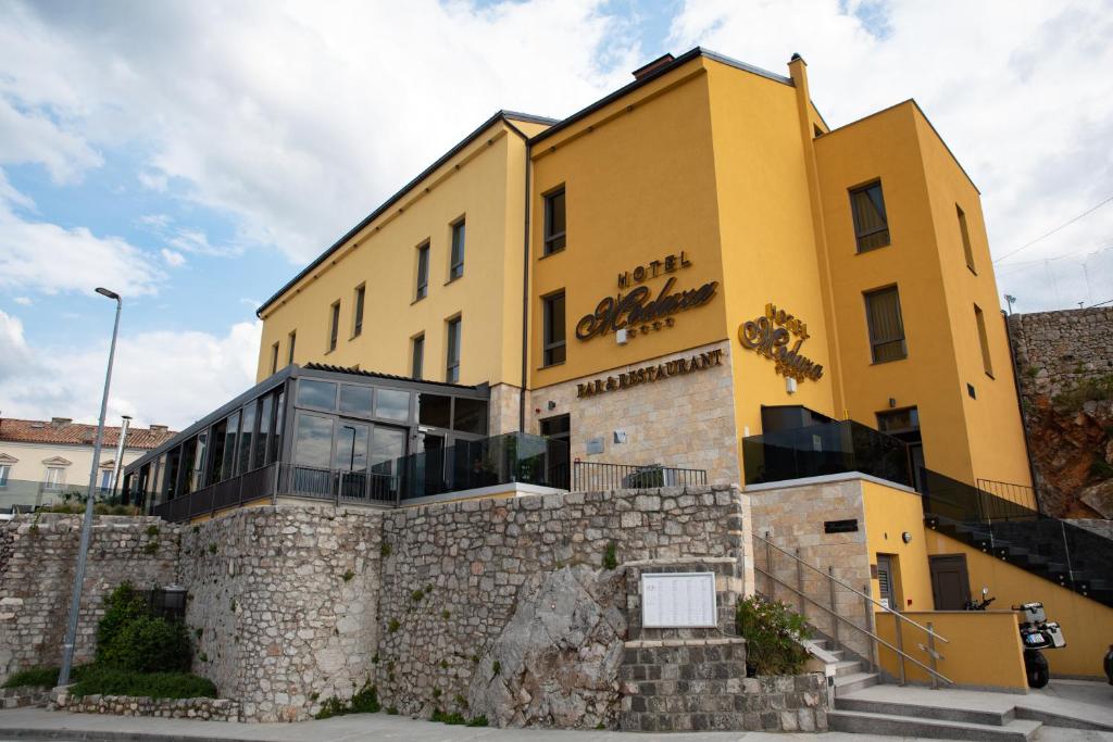 a yellow building on top of a stone wall at Hotel Meduza in Senj