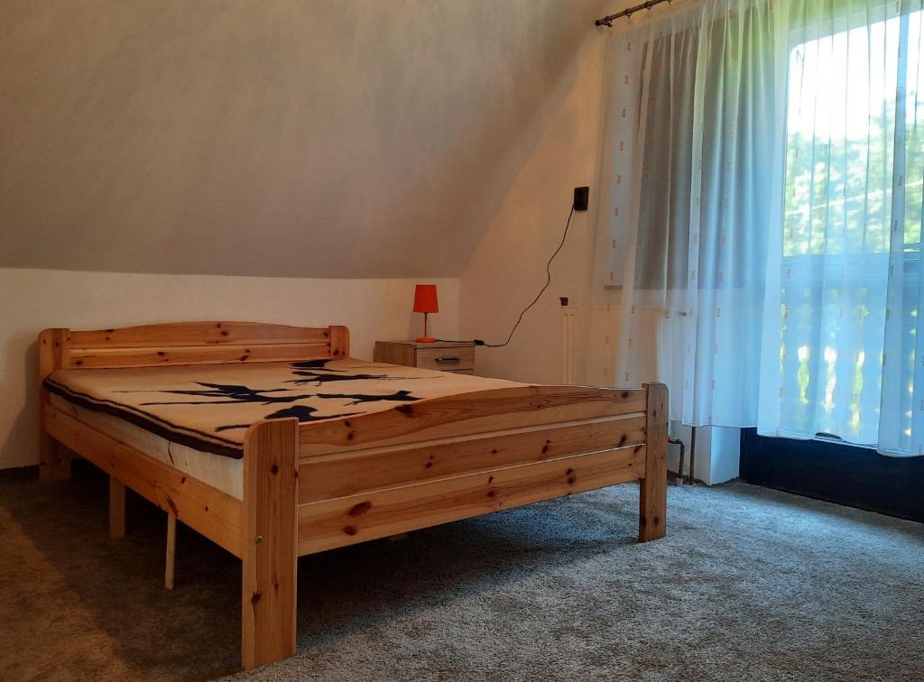 a bedroom with a wooden bed and a window at Vadása Nyaralóház in Őrimagyarósd