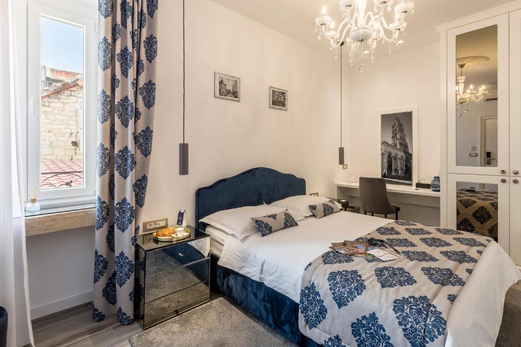 een slaapkamer met een bed, een raam en een kroonluchter bij Elixir luxury rooms in Split
