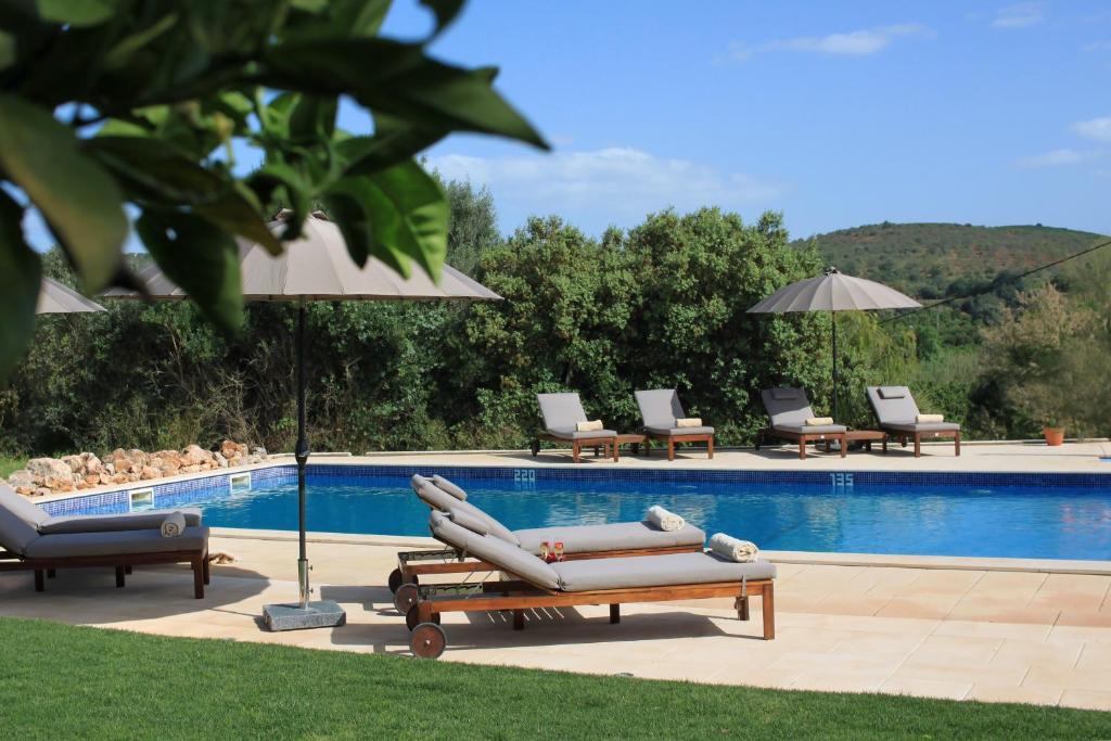 a pool with two lounge chairs and an umbrella at Quinta da Luz - A Luxury Boutique B&B in Silves