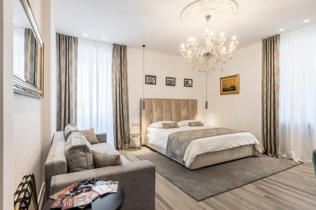 een slaapkamer met een bed, een bank en een kroonluchter bij Elixir luxury rooms in Split