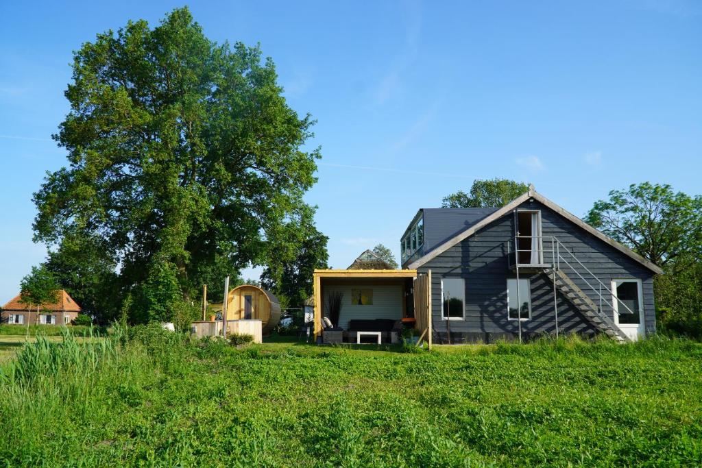 a black house on a grassy hill at Groepsverblijf "De Klosse" in Wanneperveen