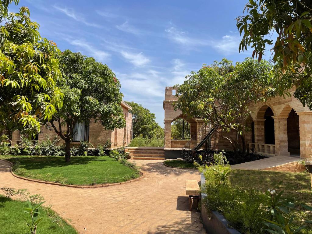 un patio de un edificio con un árbol y un banco en The Postcard Gir Wildlife Sanctuary, en Sasan Gir