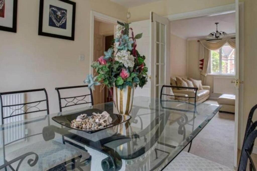 Luxury 4 Bedroom House في مانشستر: غرفة معيشة مع طاولة زجاجية و مزهرية مع الزهور