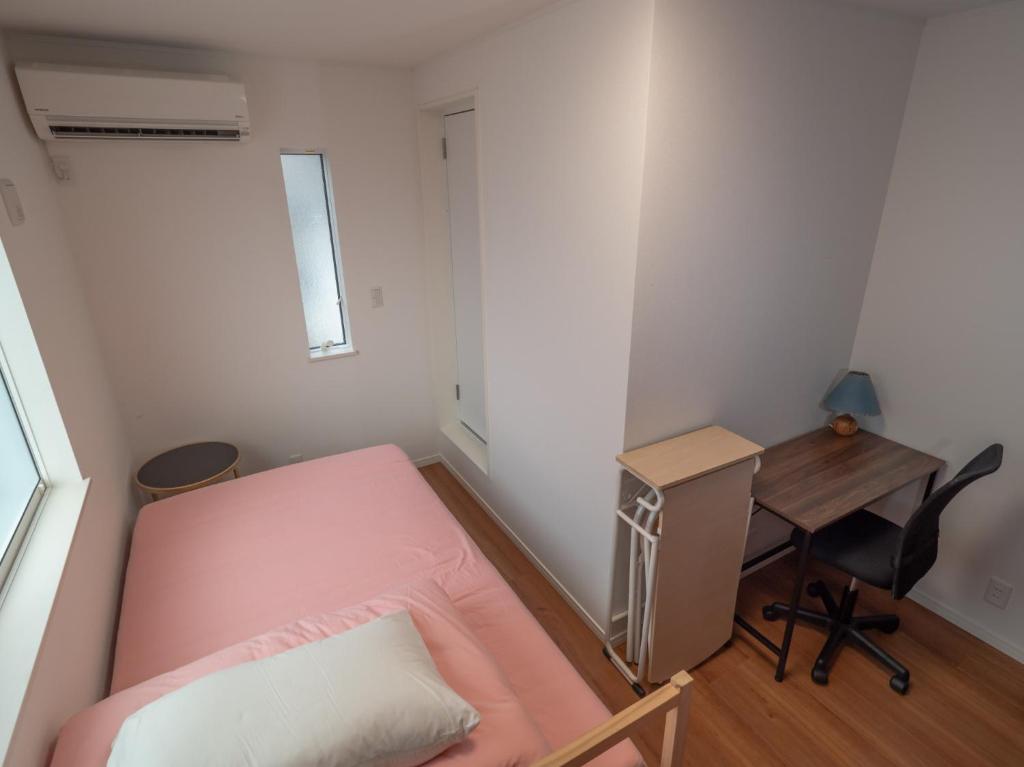 a small bedroom with a pink bed and a desk at Kamakura International House Double Room w Shower Toilette - Vacation STAY 11408 in Kamakura