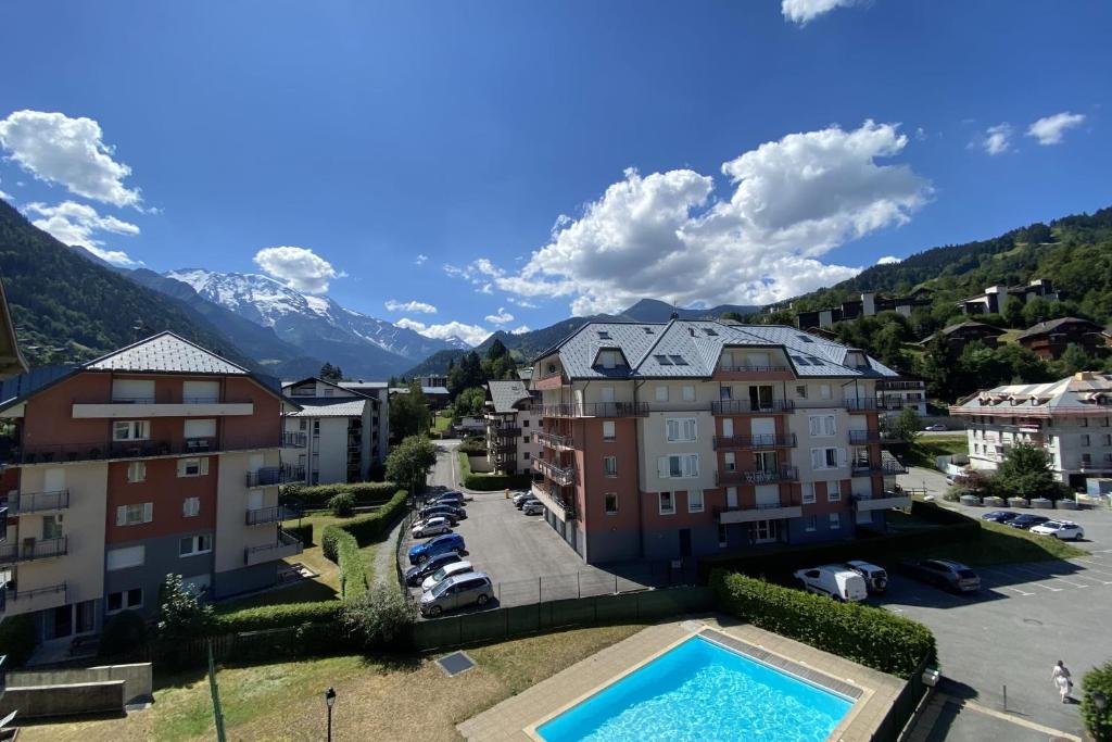 un complexe avec une piscine et des montagnes en arrière-plan dans l'établissement Flat In Residence With Swimming Pool, à Saint-Gervais-les-Bains