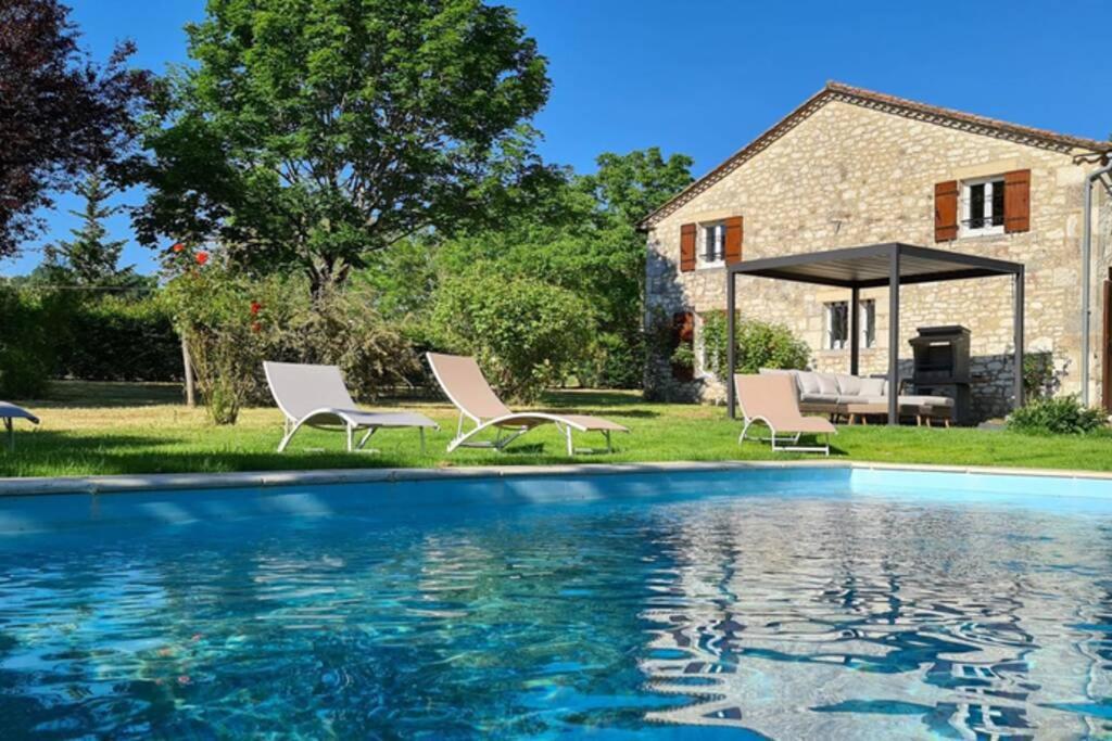 una piscina con sedie e una casa sullo sfondo di Gîte de charme piscine privée chauffée climatisé wifi aux portes du Périgord entre Villeréal et Monpazier a Parranquet