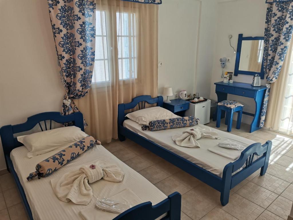 2 Betten in einem Zimmer mit blauen Möbeln und einem Spiegel in der Unterkunft Aiantas in Ermoupoli