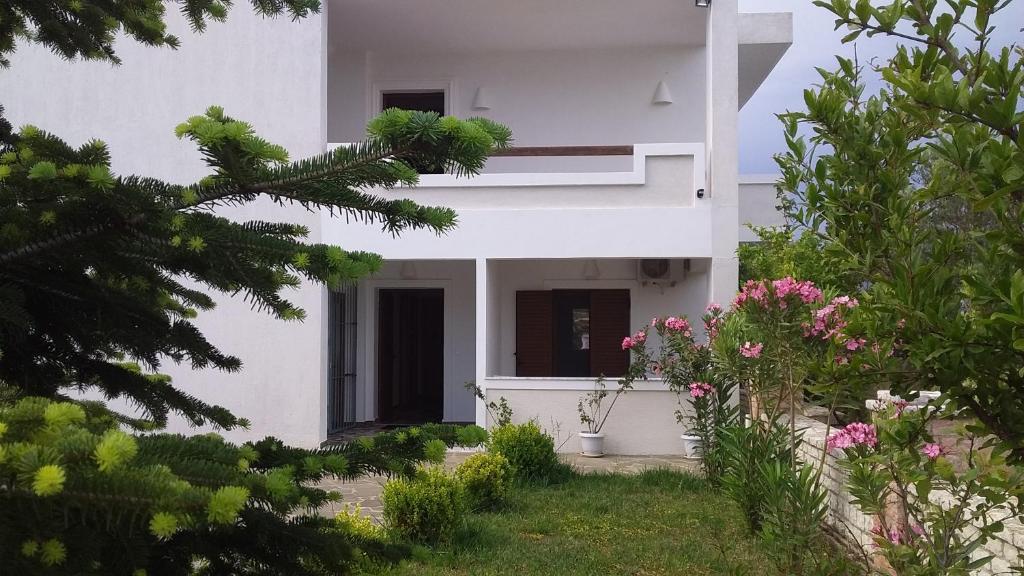 a white house with flowers in the yard at Mihal Suites in Sarandë