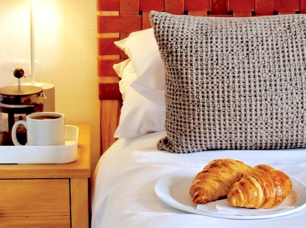 a plate of croissants on a bed with a cup of coffee at Townhouse Exeter in Exeter