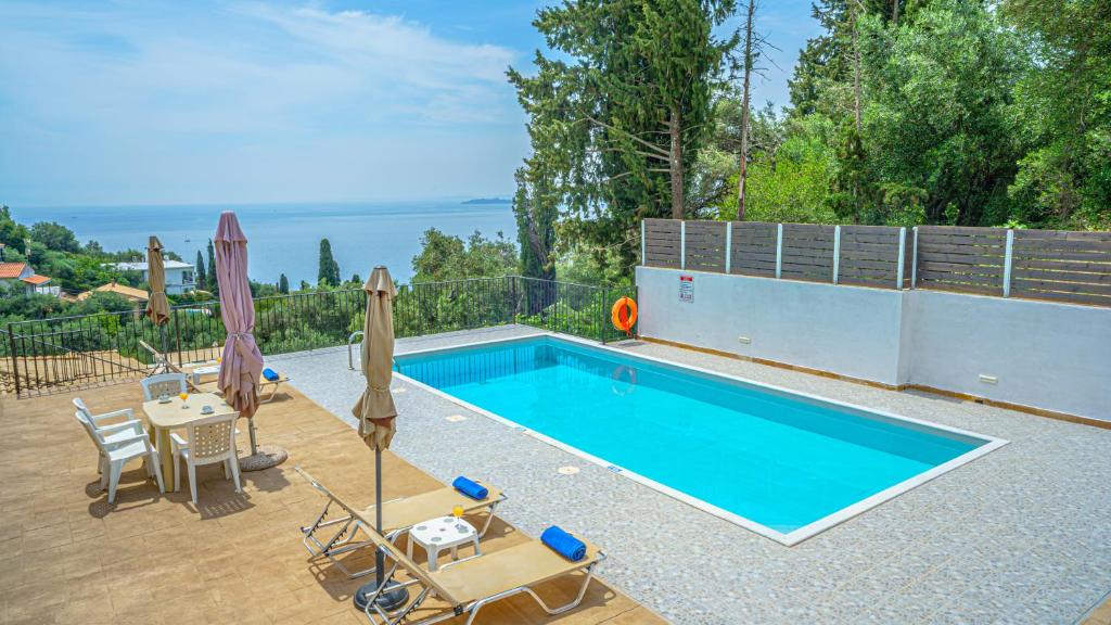 a swimming pool with two chairs and a table and umbrellas at Apartment Zeus 2-The infinity view in Nisaki