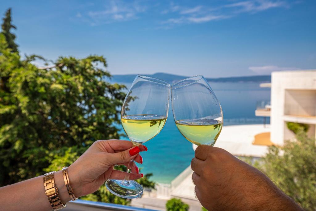 two people holding up glasses of white wine at Apartmani Maya in Selce