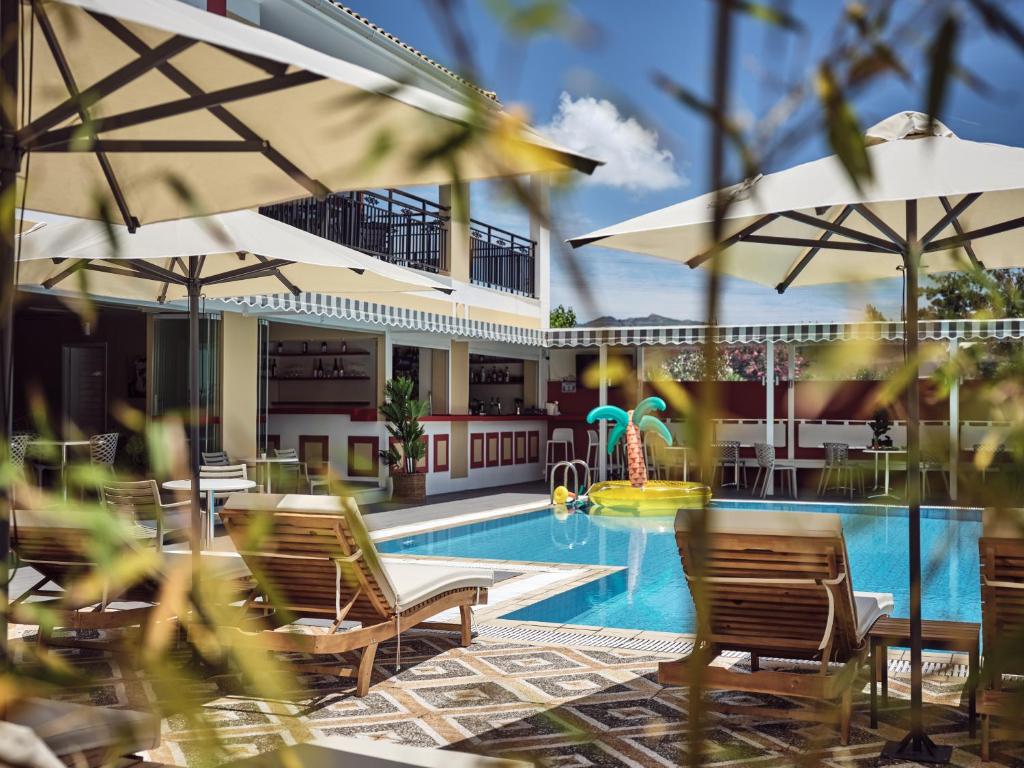 una piscina con sillas y sombrillas junto a un complejo en Cactus Hotel, en Laganas