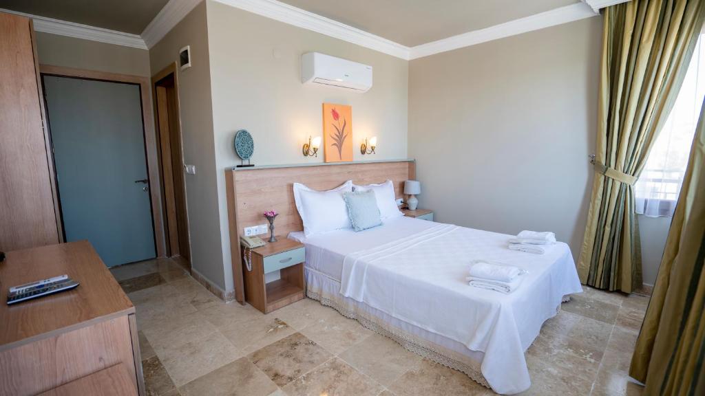 - une chambre avec un lit blanc et un bureau dans l'établissement Ebruli Hotel Cunda, à Ayvalık