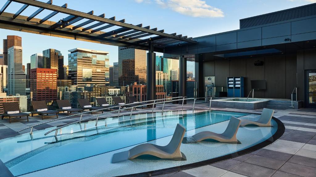 a pool on top of a building with a city skyline at The Rally Hotel at McGregor Square in Denver