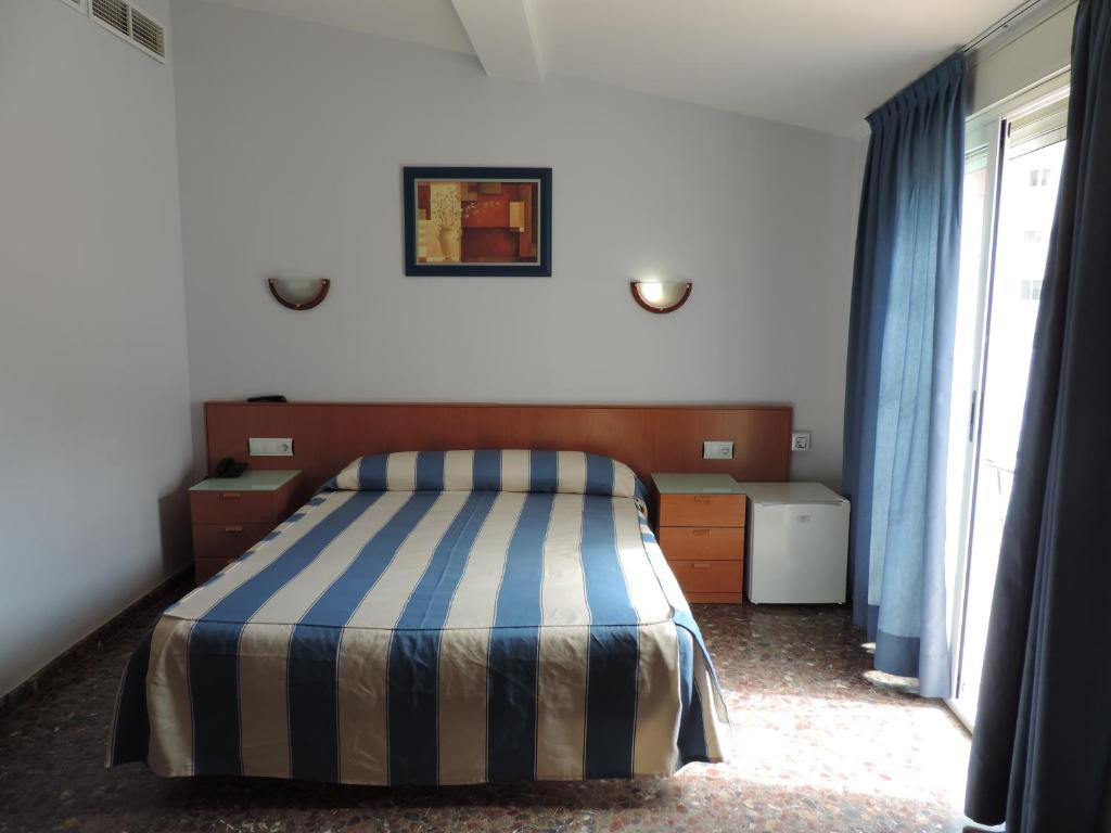 1 dormitorio con 1 cama con manta a rayas en Hotel Costa San Antonio, en Cullera
