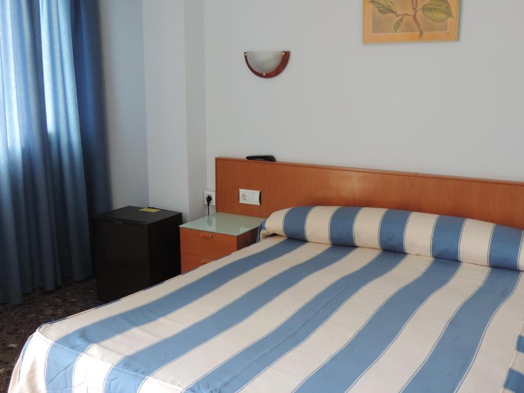 a bedroom with a bed with blue and white stripes at Hotel Costa San Antonio in Cullera