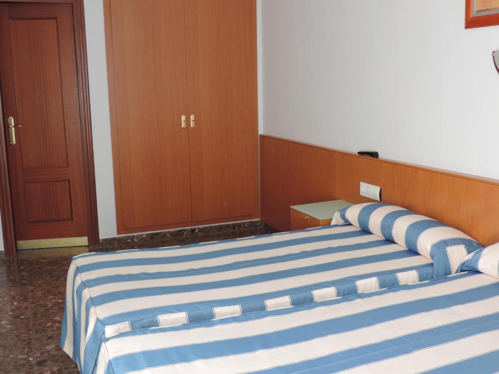 a bedroom with two beds with blue and white stripes at Hotel Costa San Antonio in Cullera