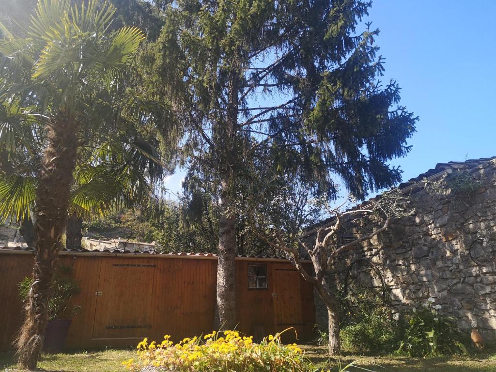 a house with a fence and two trees at Logement cosy verdoyant RDC avec piscine in Charmes-sur-Rhône