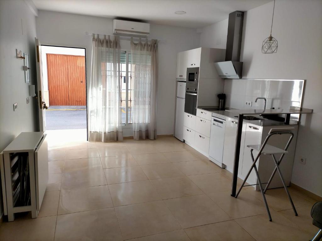 een keuken met witte apparatuur en een deur naar een kamer bij Apartamento avenida de la musica in Conil de la Frontera