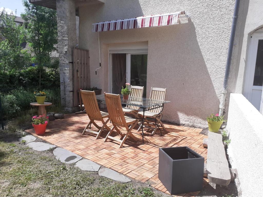 een patio met een tafel en stoelen en een televisie bij Appartement rez de chaussée avec terrasse et jardin in Tence