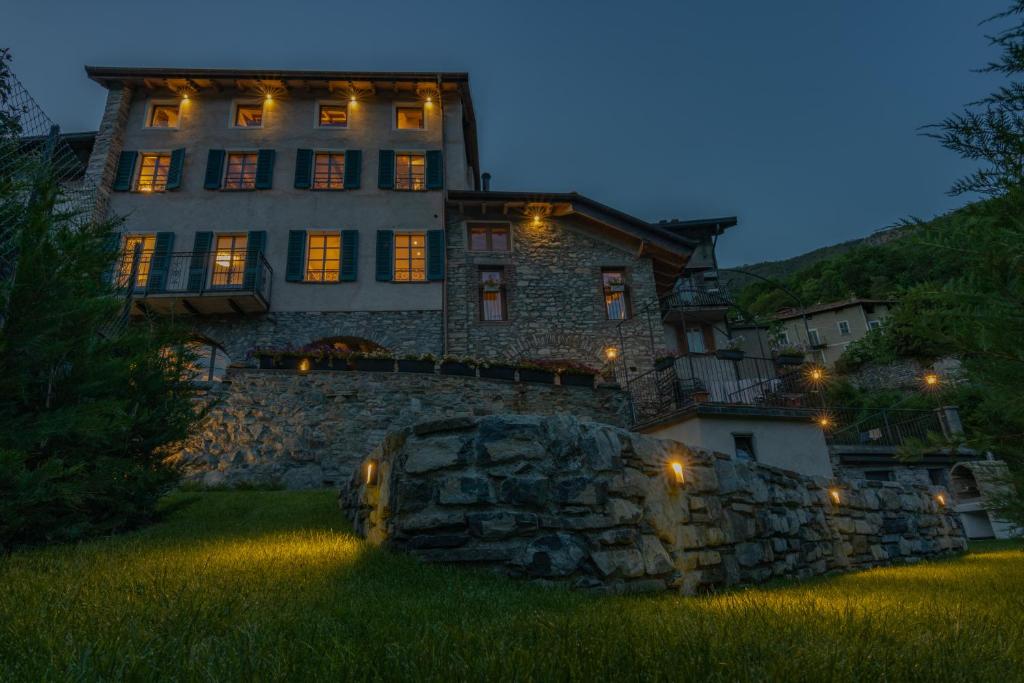 Cette grande maison en pierre est éclairée la nuit. dans l'établissement Cà Piodèe, à Faggeto Lario 