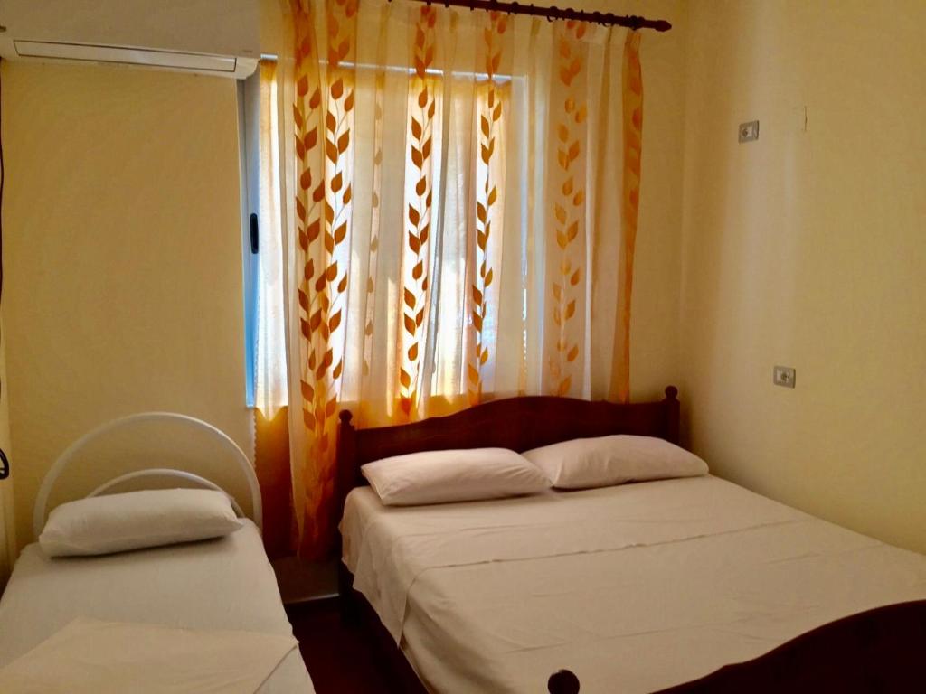 2 Betten in einem kleinen Zimmer mit Fenster in der Unterkunft Shyqi Apartments in Velipojë