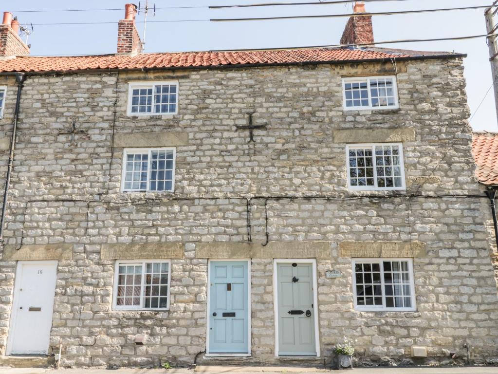 an old stone building with blue doors and windows at Crooked Cottage in Kirkbymoorside