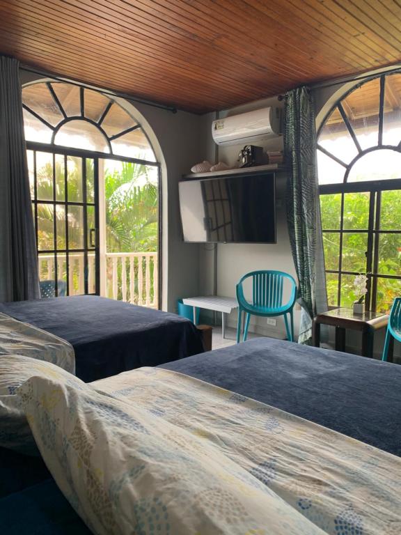 two beds in a room with two windows at Sarah's Place San Andres in San Andrés